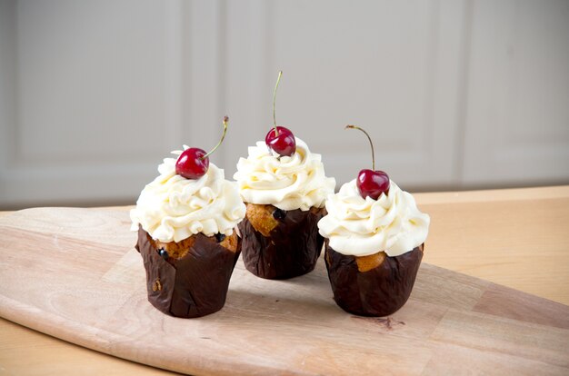 Tre dolci cupcakes con crema e ciliegia