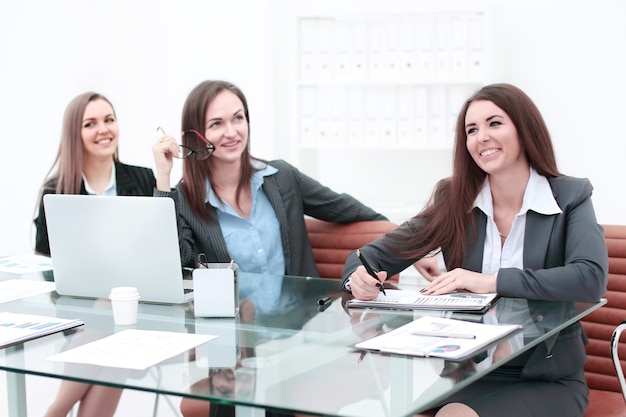 Tre donne d'affari che si incontrano intorno al tavolo in un ufficio moderno