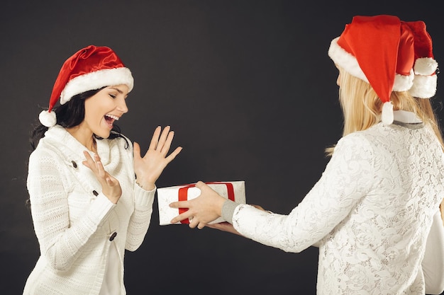 Tre donne in costume di Babbo Natale con lo shopping natalizio