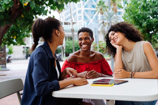 Tre donne ispaniche e nere di razza mista che si uniscono all'aperto