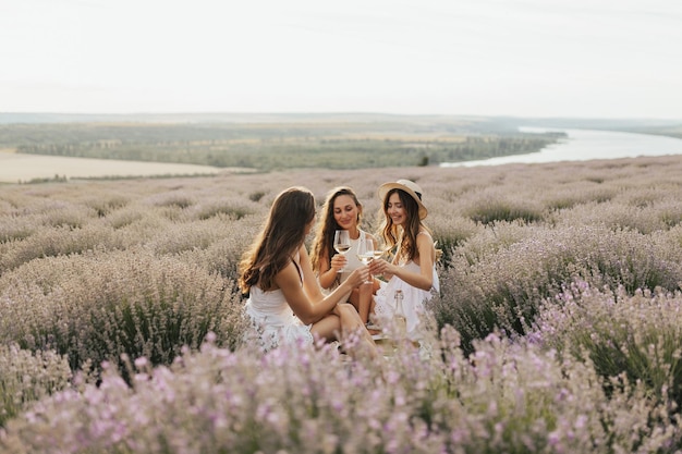 Tre donne vestite di bianco sono sedute in un campo di lavanda.