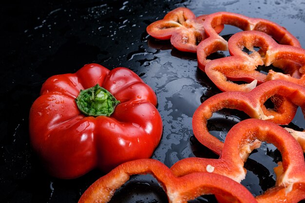 Tre fette di peperoni rossi e arancioni. Sfondo nero.