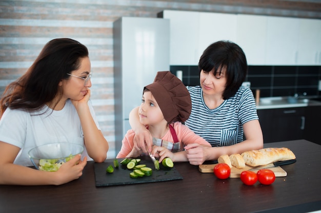 Tre generazioni di donne cucinano in cucina. Nonna, madre e nipote trascorrono del tempo insieme a casa.