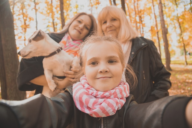 Tre generazioni di donne e cani si divertono a guardare insieme la telecamera in posa per un autoritratto