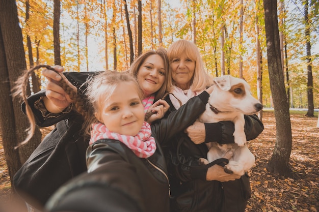 Tre generazioni di donne e cani si divertono a guardare insieme la telecamera in posa per un autoritratto