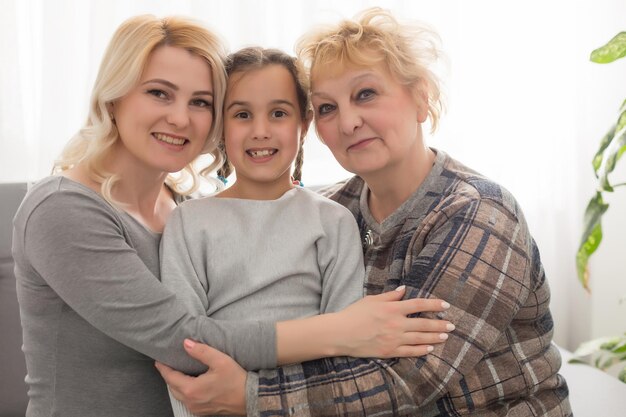 Tre generazioni di donne. La bella donna e l'adolescente stanno baciando la loro nonna mentre sono seduti sul divano a casa
