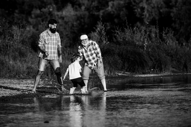 Tre generazioni di famiglia che saltano le pietre con papà e nonno tre generazioni diverse età grand...