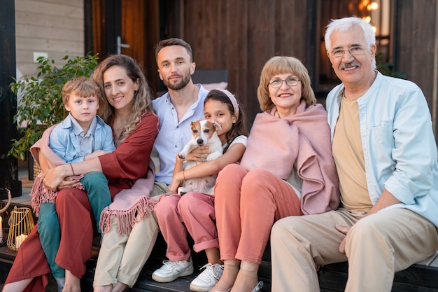 Tre generazioni di una famiglia seduti vicino alla loro casa di campagna