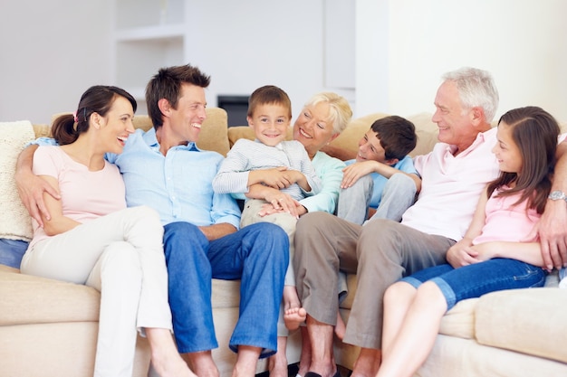 Tre generazioni si riuniscono felicemente insieme Tre generazioni di famiglie sedute insieme affettuosamente sul divano