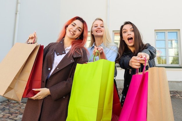 Tre giovani amiche con borse colorate dopo lo shopping