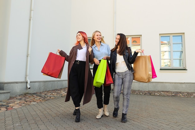 Tre giovani amiche con sacchetti colorati dopo lo shopping