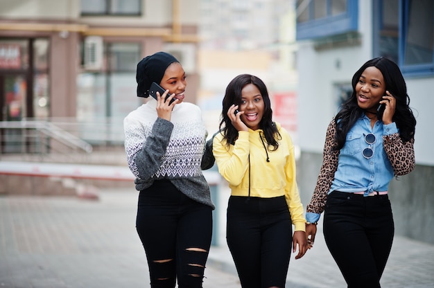 Tre giovani amici afroamericani della donna dell'università con i telefoni cellulari.