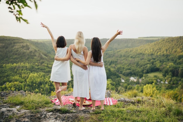 Tre giovani donne che tengono le loro mani in alto