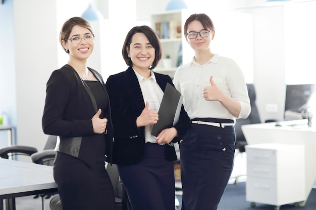 Tre giovani donne d'affari di successo in ufficio che sorridono felicemente