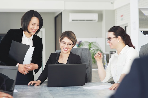 Tre giovani donne d'affari di successo in ufficio lavorano insieme felicemente a un progetto