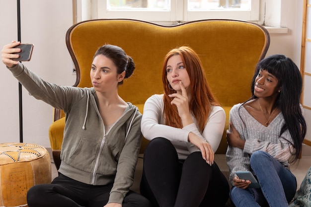 Tre giovani ragazze che prendono un selfie mentre fanno facce buffe ed espressioni sciocche