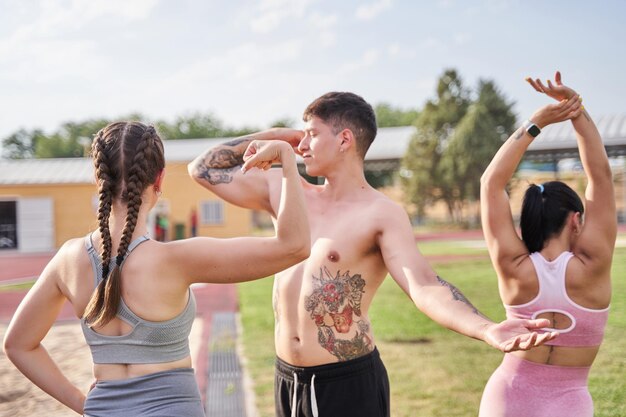 Tre giovani sportivi in posa ritratto di amici che si allungano dopo l'allenamento