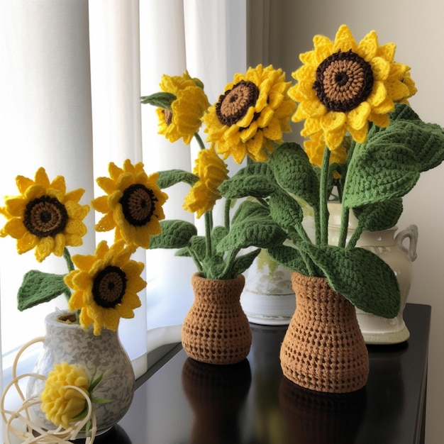 Tre girasoli all'uncinetto sono su un tavolo con un vaso.