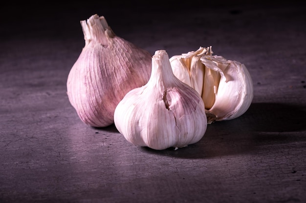 Tre grandi teste di aglio rosa su un piano di lavoro in cucina