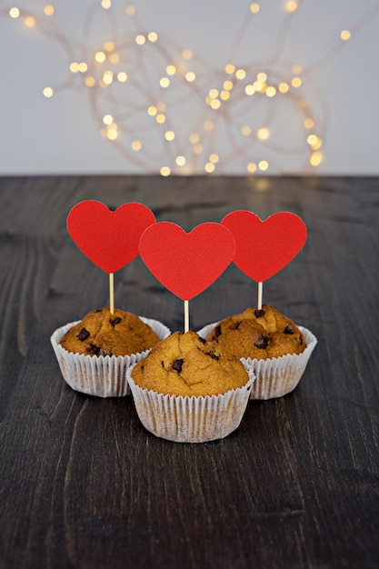 Tre gustosi muffin al cioccolato con grandi cuori rossi