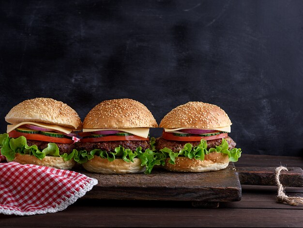 Tre hamburger con verdure su una tavola di legno marrone