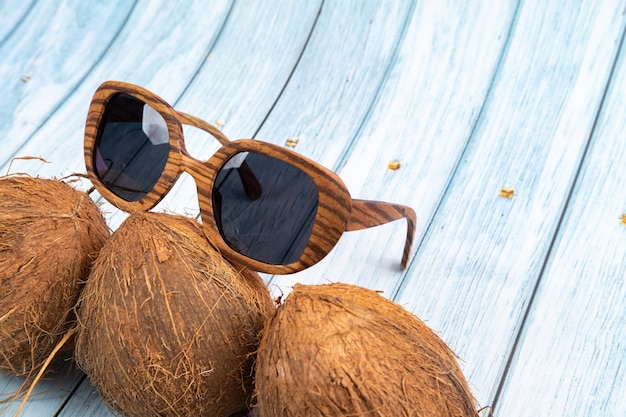 Tre intere noci di cocco e bicchieri di legno su uno sfondo di legno blu.