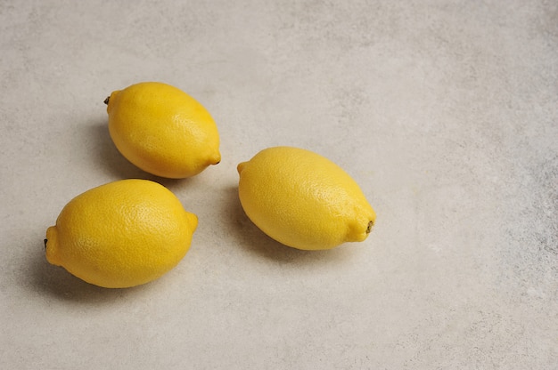 Tre interi limoni gialli su una superficie grigia