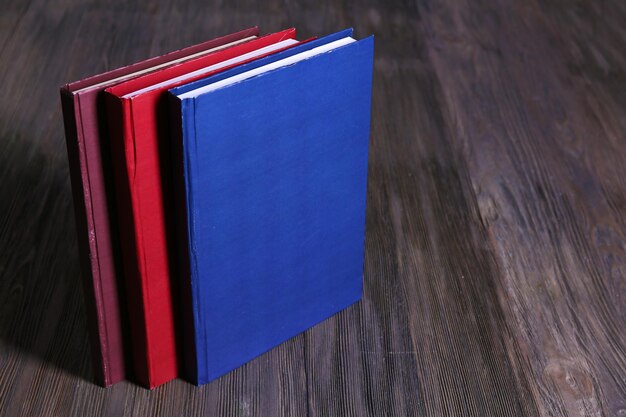 Tre libri colorati su sfondo di legno