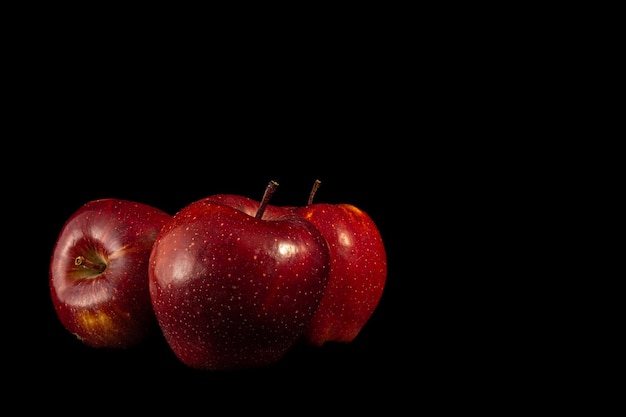 Tre mele rosse su uno sfondo nero, ideali per le carte da parati.