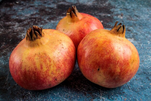 Tre melograni appetitosi su fondo rustico.