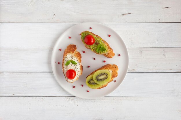 Tre mini panini su un piatto su fondo di legno bianco