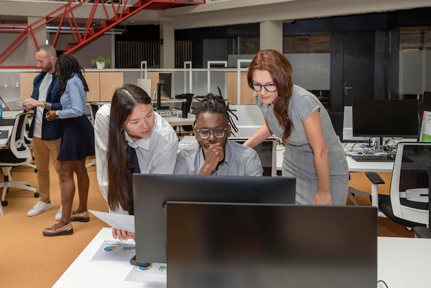 Tre partner commerciali multietnici che lavorano a un progetto su un computer in uno spazio di coworking