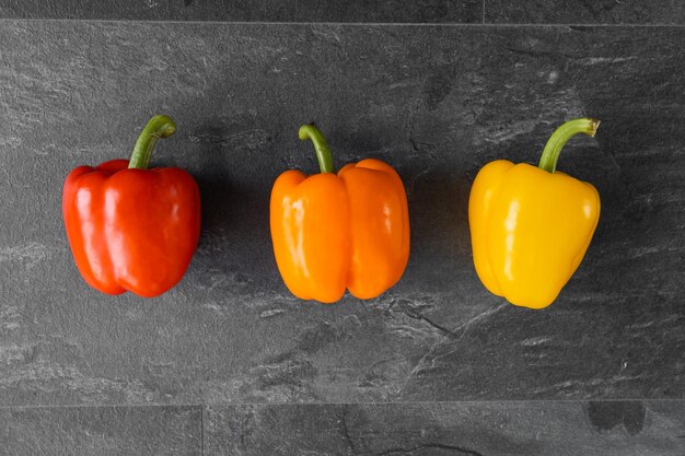 Tre peperoni su sfondo scuro verdure per il ristorante verdure su sfondo bianco