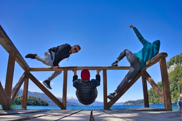 tre persone che si esercitano simmetricamente all'aperto davanti al lago quando fa freddo sulla ringhiera. Q alta