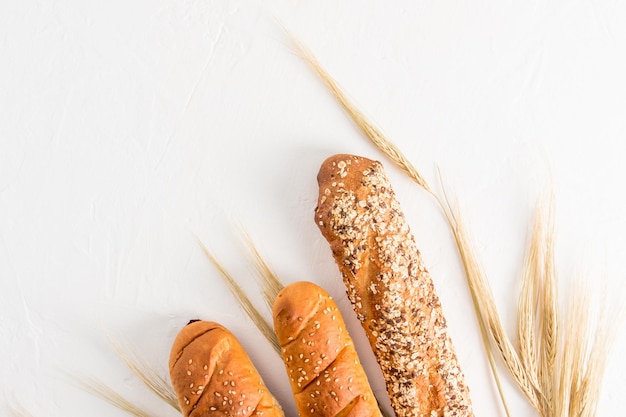 Tre pezzi di baguette tritate su uno sfondo bianco con spighe di grano vista dall'alto sfondo bianco una copia dello spazio