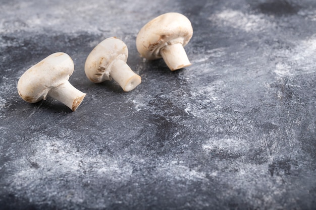 Tre pezzi di funghi champignon maturi posti sul tavolo di marmo.