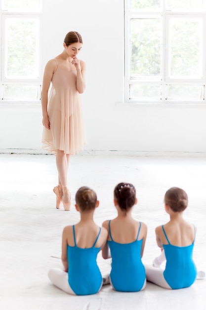 Tre piccole ballerine che ballano con un insegnante di balletto personale nello studio di danza