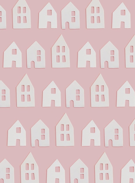 Tre piccole case bianche in ceramica con finestre su sfondo rosa piatto. Idea minima di carta creativa o carta da parati Vista dall'alto