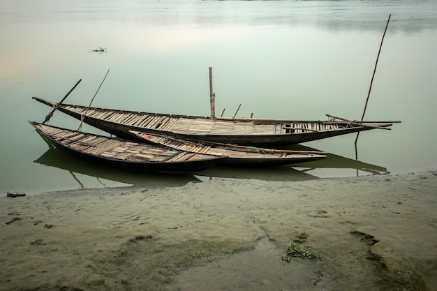 Tre piccole e grandi barche passeggeri stanno aspettando l'acqua del fiume nella mattina d'inverno Uno scenario nostalgico e lunatico