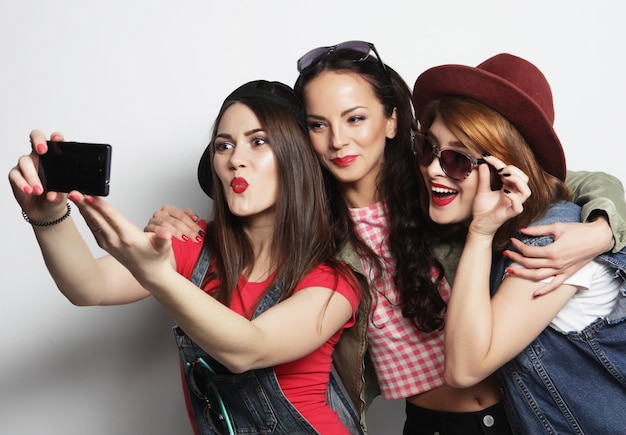 Tre ragazze alla moda hipster migliori amiche che prendono selfie con il telefono cellulare