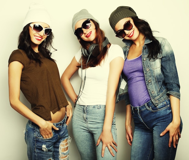 Tre ragazze alla moda sexy hipster migliori amiche. Stare insieme e divertirsi. Su sfondo grigio.