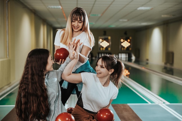 Tre ragazze allegre che danno il cinque al club di bowling.