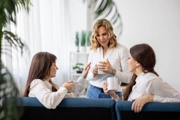 Tre ragazze discutono di notizie e bevono il tè nell'appartamento