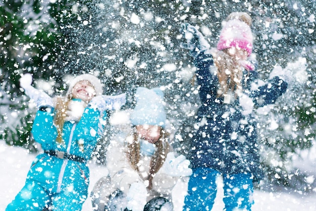 Tre ragazze felici che vomitano la neve nella foresta