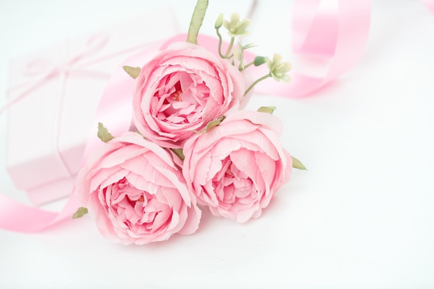 Tre rose rosa con nastro e confezione regalo sul tavolo bianco Concetto di San Valentino