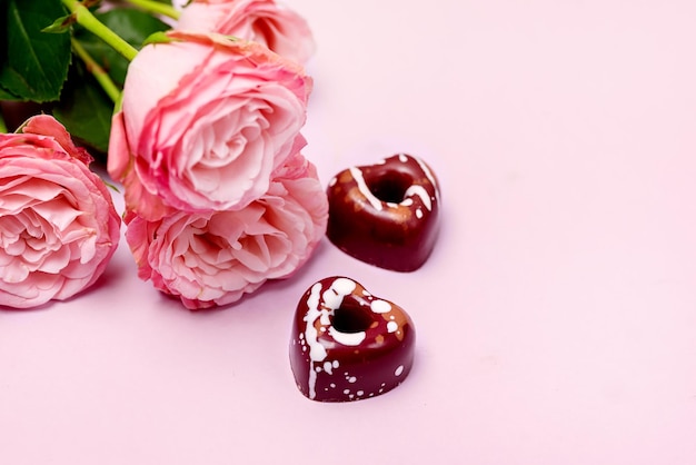 Tre rose rosa gustose caramelle fatte in casa a forma di cuori su sfondo rosa il giorno di San Valentino concetto o carta vacanze sfondo spazio copia vista dall'alto