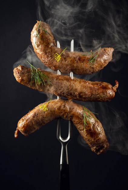 Tre salsicce di manzo fritte su una forchetta Il concetto di un delizioso pranzo per un hotel su sfondo nero