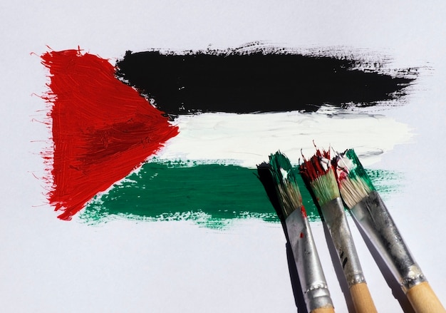 Tre spazzole sulla bandiera della Palestina che dipingono su uno sfondo di carta bianca, messa a fuoco selezionata.