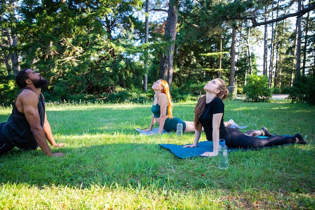 Tre sportivi durante un allenamento insieme esercizi di stretching