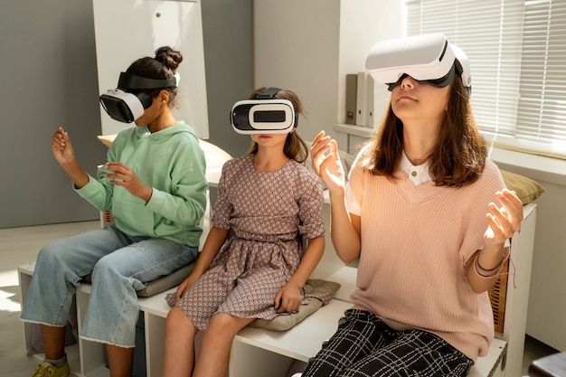 Tre studentesse in cuffie vr che guardano una presentazione 3d